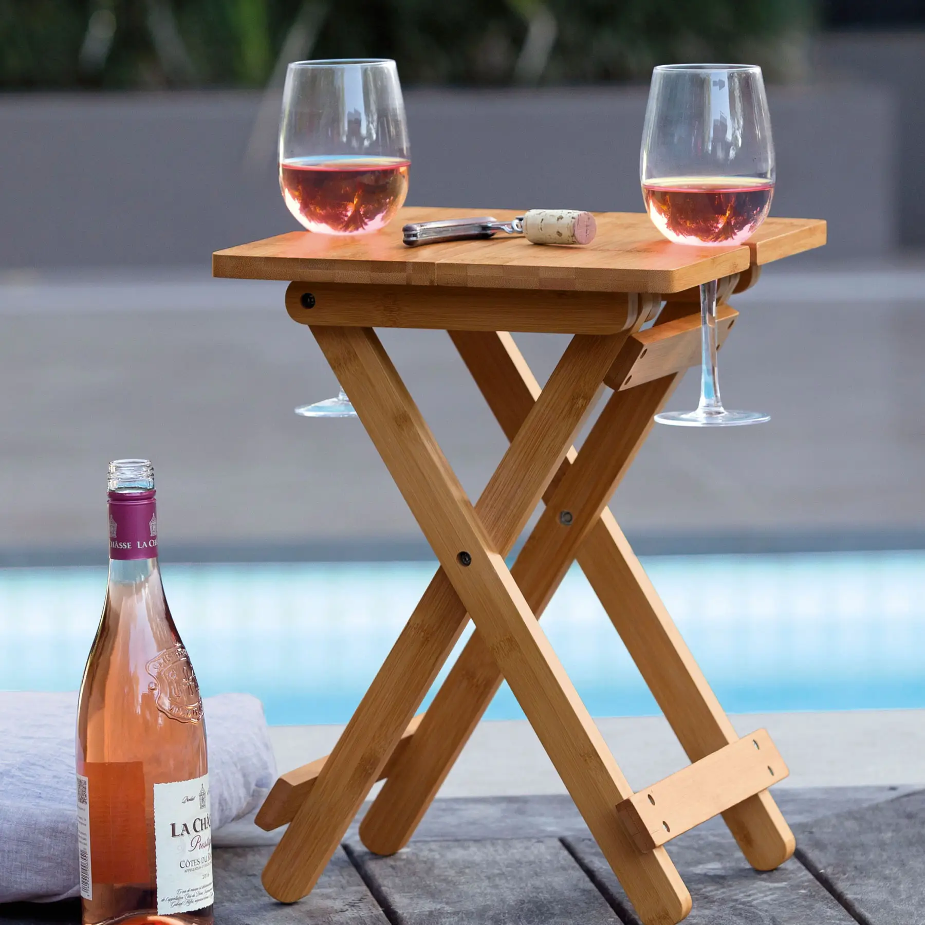 Portable Picnic Table with Wine Glass Holders holding wine glasses beside a pool